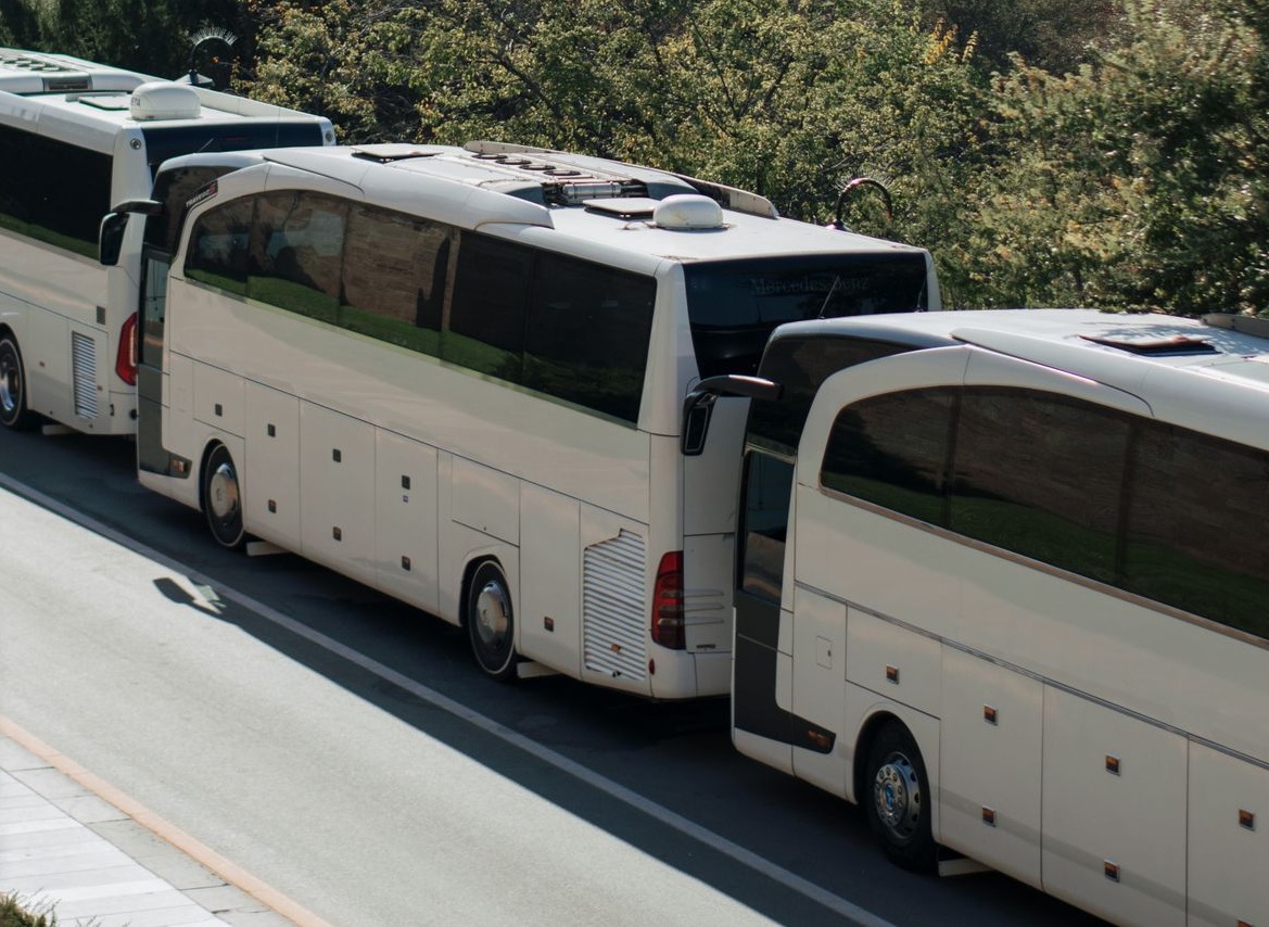 LuxBusExpress luxury motorcoaches staged against city skyline backdrop